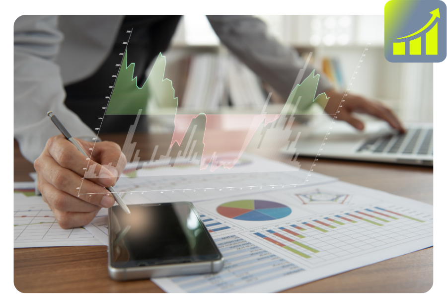 Eine Person ist an einem Schreibtisch mit Papieren, Laptop, Mobiltelefon und einer virtuellen, in der Luft schwebenden Grafik.